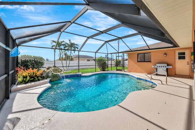 view of pool featuring pool water feature, glass enclosure, a patio area, and a grill