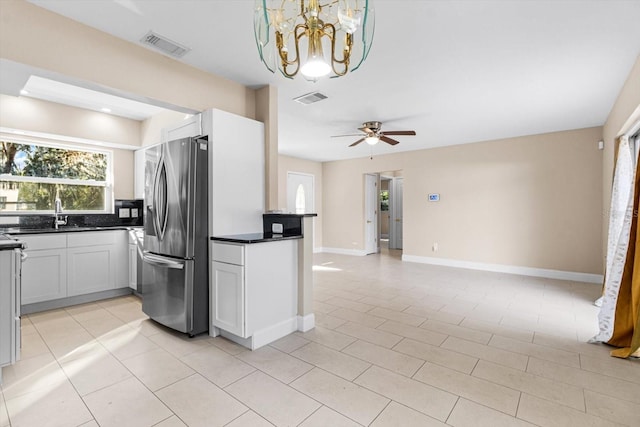 kitchen with white cabinets, ceiling fan with notable chandelier, sink, stainless steel refrigerator with ice dispenser, and light tile patterned flooring