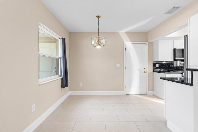 unfurnished dining area with a notable chandelier and light tile patterned flooring