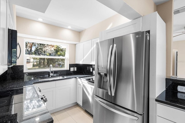 kitchen with sink, stainless steel refrigerator with ice dispenser, decorative backsplash, dark stone countertops, and white cabinetry