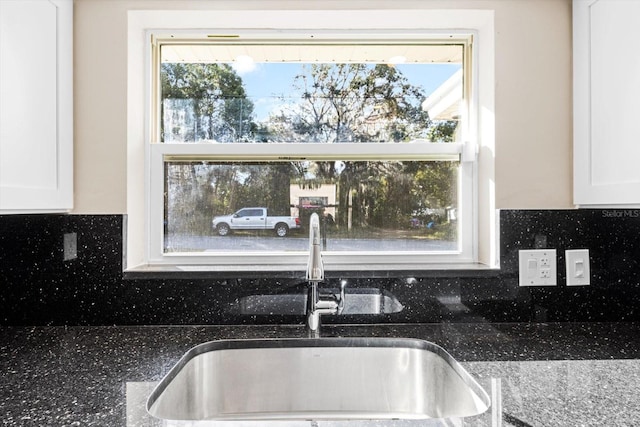 kitchen featuring white cabinets, decorative backsplash, sink, and stone counters