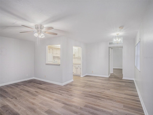 unfurnished room featuring ceiling fan with notable chandelier, light wood-type flooring, and a textured ceiling