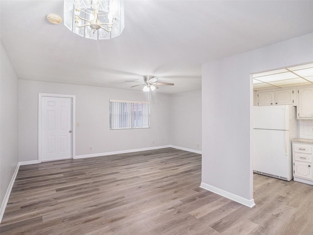 unfurnished living room with light wood-type flooring and ceiling fan with notable chandelier