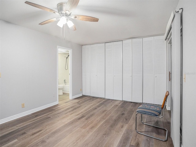 bedroom with hardwood / wood-style flooring, ceiling fan, connected bathroom, and a closet