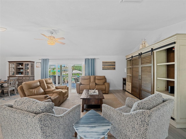 living room with lofted ceiling, a barn door, wood-type flooring, and ceiling fan