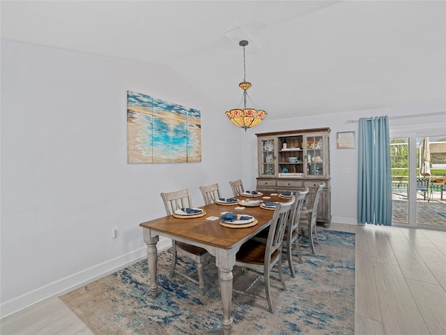 dining room with vaulted ceiling and light wood-type flooring