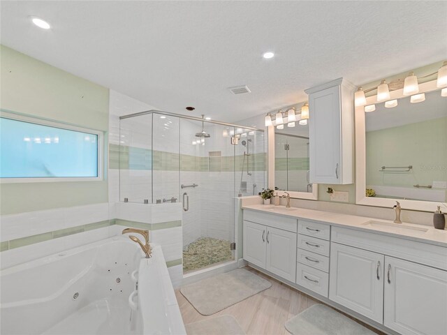 bathroom with plus walk in shower, a textured ceiling, and vanity