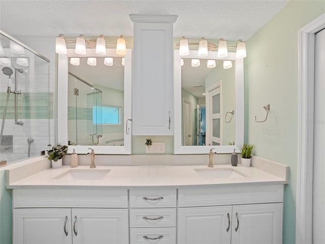 bathroom with vanity, an enclosed shower, and a textured ceiling