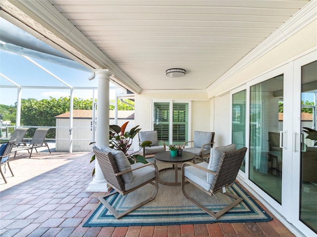 view of patio with a lanai, a storage shed, and french doors