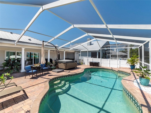 view of pool featuring glass enclosure, a patio, and a hot tub