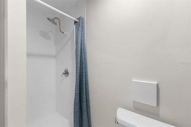 bathroom featuring a shower with curtain and toilet