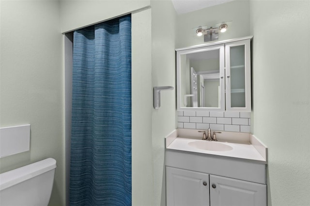 bathroom with decorative backsplash, vanity, toilet, and curtained shower