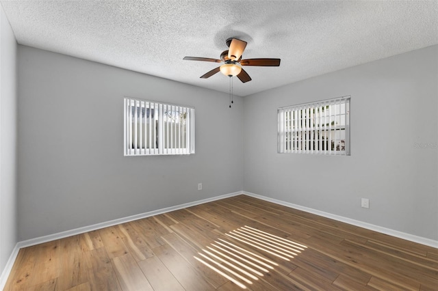 spare room with plenty of natural light, ceiling fan, wood-type flooring, and a textured ceiling