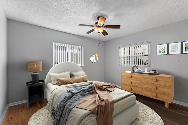 bedroom with a textured ceiling, dark hardwood / wood-style floors, and ceiling fan