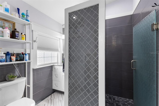 bathroom with a shower, toilet, and tile walls