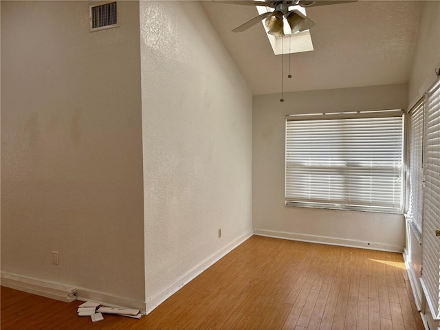 empty room with ceiling fan, light wood-type flooring, and vaulted ceiling