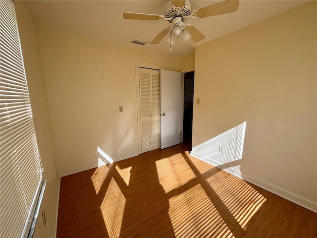 unfurnished bedroom featuring ceiling fan, dark hardwood / wood-style floors, and a closet