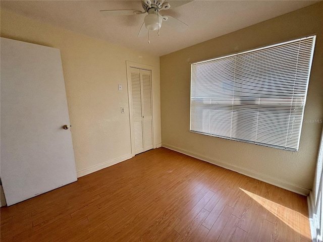 unfurnished bedroom featuring a closet, light hardwood / wood-style flooring, and ceiling fan