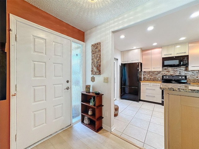 kitchen with backsplash, black appliances, a textured ceiling, light tile patterned flooring, and white cabinetry