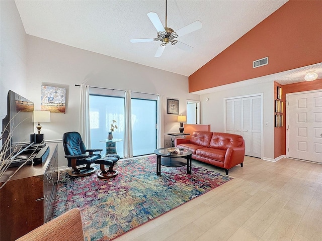 living room featuring ceiling fan, light hardwood / wood-style floors, a textured ceiling, and high vaulted ceiling