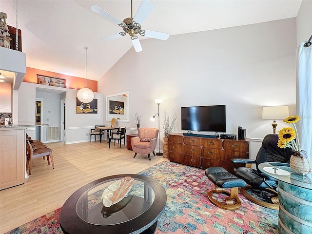 living room with ceiling fan, high vaulted ceiling, and light hardwood / wood-style floors