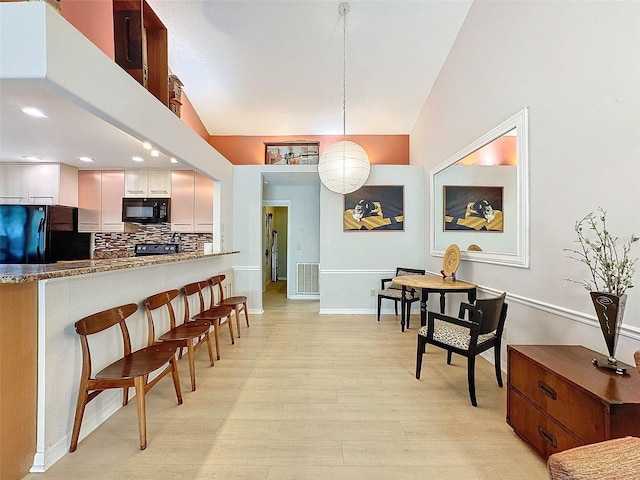 kitchen with light hardwood / wood-style flooring, backsplash, decorative light fixtures, white cabinets, and black appliances