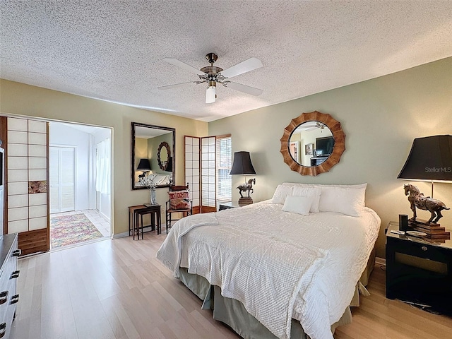 bedroom featuring ceiling fan, light hardwood / wood-style floors, and a textured ceiling