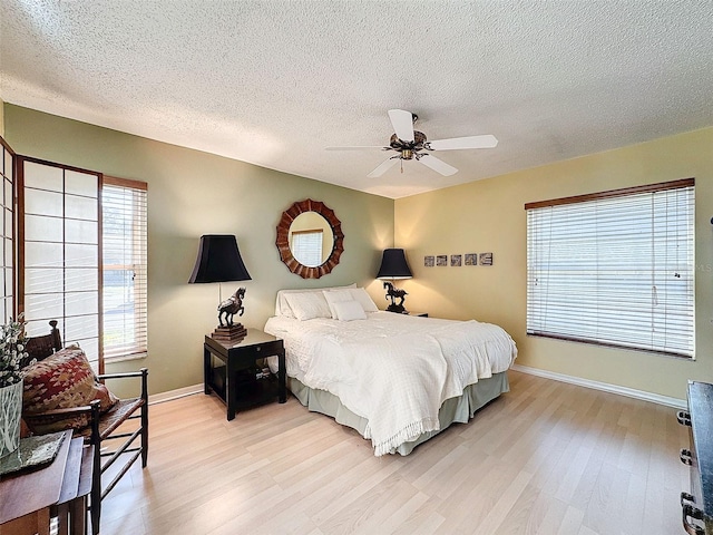 bedroom featuring ceiling fan, light hardwood / wood-style flooring, and a textured ceiling