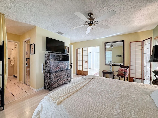 bedroom featuring ensuite bathroom, ceiling fan, a textured ceiling, and light hardwood / wood-style flooring