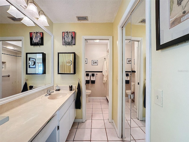 bathroom featuring tile patterned flooring, vanity, a textured ceiling, and toilet