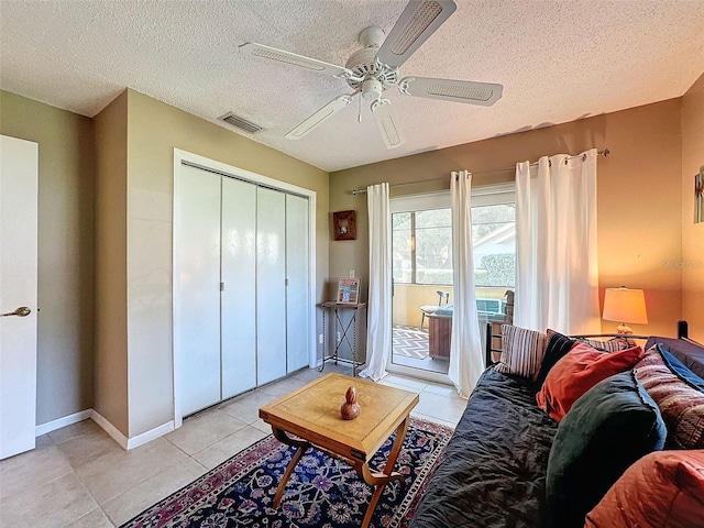 tiled living room featuring ceiling fan and a textured ceiling