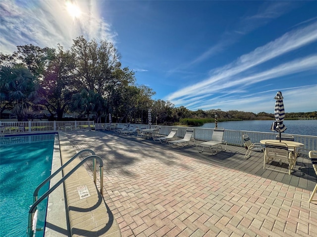 view of swimming pool featuring a water view and a patio