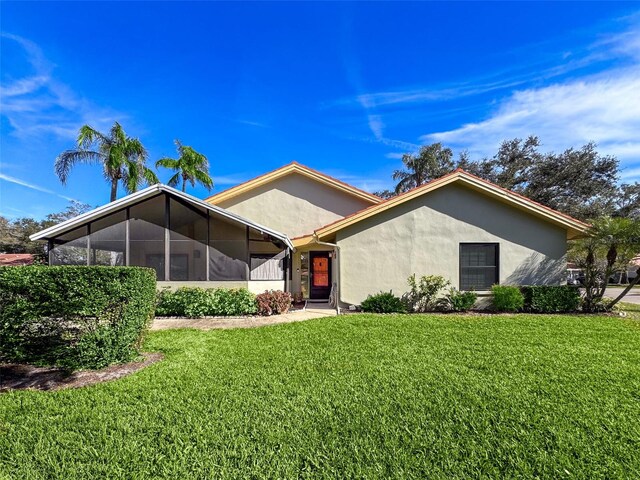 view of front of home featuring stucco siding, a front yard, and a sunroom
