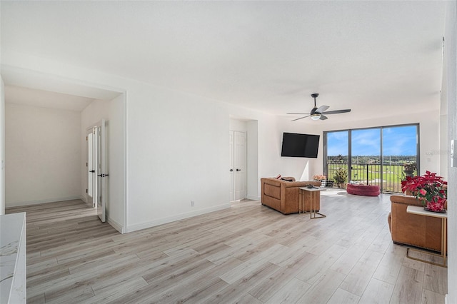 living room featuring ceiling fan, expansive windows, and light wood-type flooring