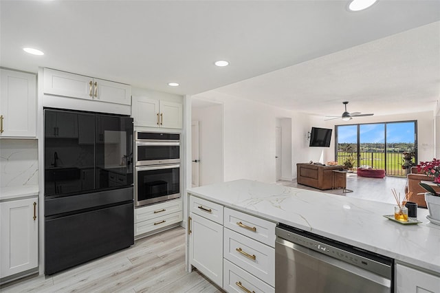 kitchen with white cabinetry, light stone countertops, backsplash, appliances with stainless steel finishes, and light wood-type flooring