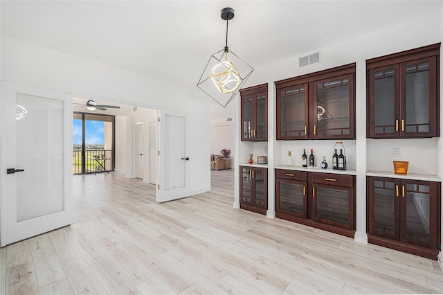 bar with dark brown cabinetry, light wood-type flooring, decorative light fixtures, and ceiling fan