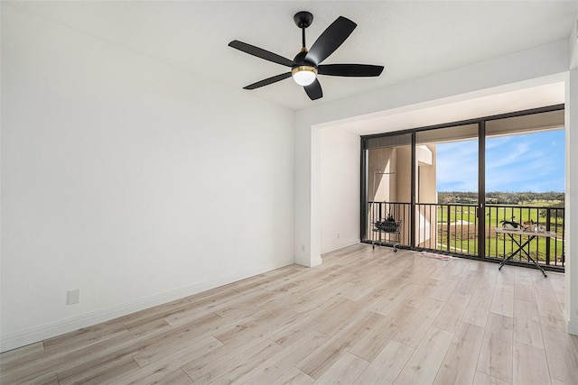 empty room with expansive windows, light hardwood / wood-style flooring, and ceiling fan