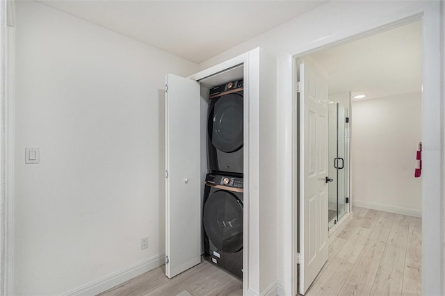 washroom with light hardwood / wood-style floors and stacked washer and clothes dryer