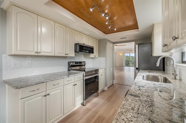 kitchen with stainless steel electric range, a raised ceiling, light stone countertops, and sink