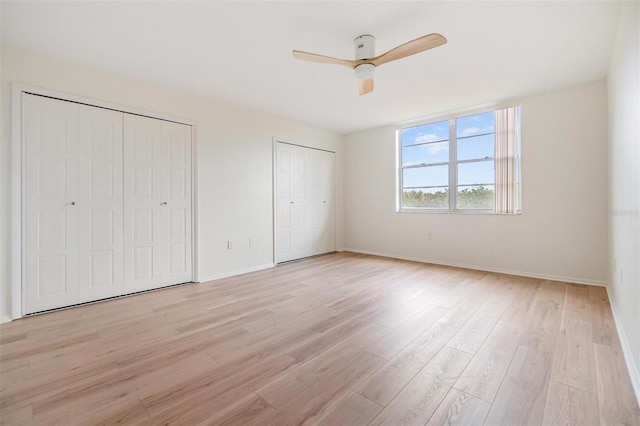 unfurnished bedroom featuring ceiling fan, two closets, and light wood-type flooring