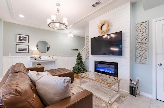 living room featuring light tile patterned floors, a large fireplace, and an inviting chandelier