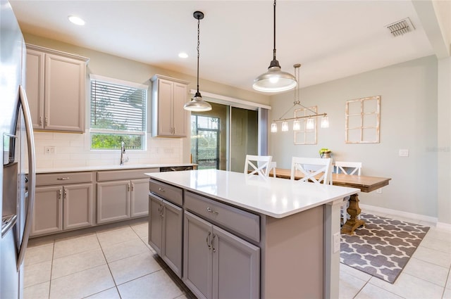 kitchen with stainless steel fridge with ice dispenser, gray cabinets, and hanging light fixtures