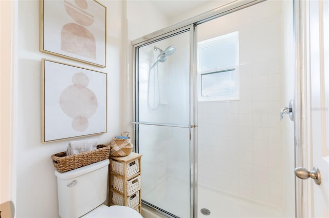 bathroom featuring a shower with door and toilet