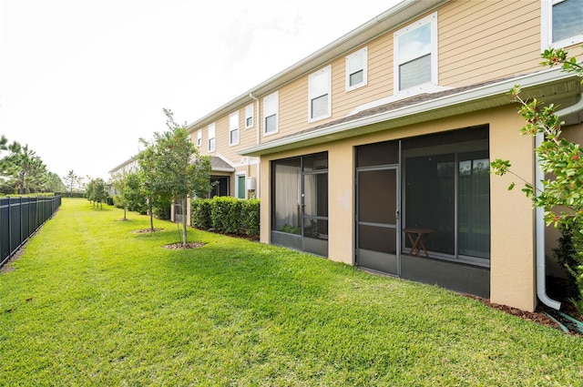 rear view of house featuring a sunroom and a yard