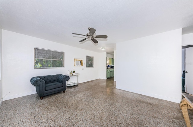 living area with ceiling fan and a textured ceiling