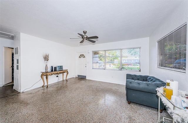 living area with a textured ceiling and ceiling fan