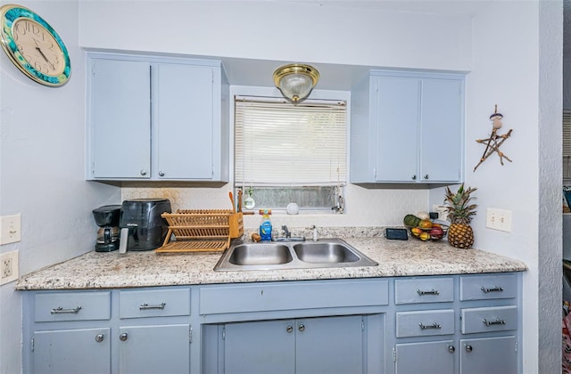 kitchen with blue cabinetry, tasteful backsplash, and sink