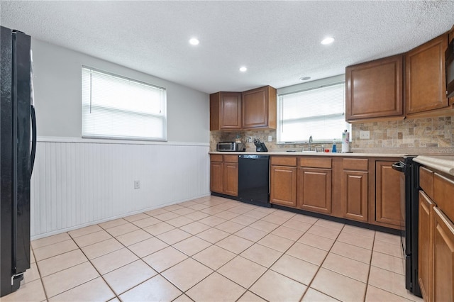 kitchen with black appliances, sink, light tile patterned floors, and a textured ceiling