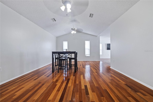 unfurnished dining area featuring a textured ceiling, dark hardwood / wood-style floors, vaulted ceiling, and ceiling fan