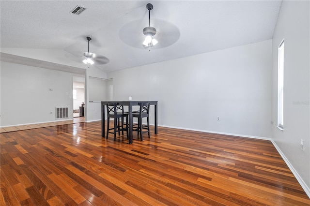 dining area featuring a textured ceiling, lofted ceiling, ceiling fan, and dark wood-type flooring